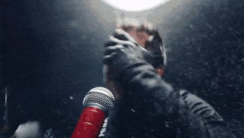 a person is holding a red microphone in front of a light