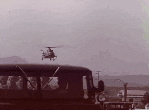 a helicopter is flying over a bus with people sitting inside