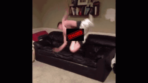 two men are wrestling on a black couch with a censored stamp on it