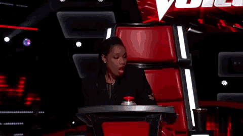 a woman is sitting in a red chair and crying .
