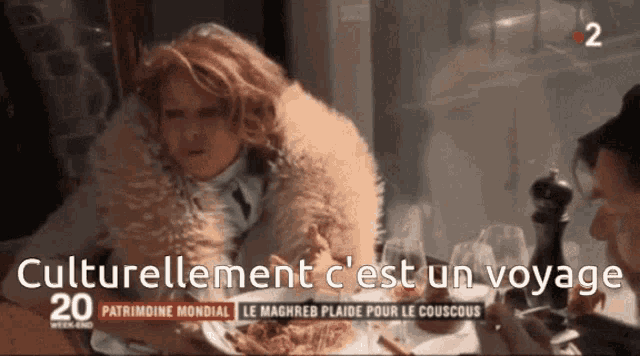 a woman in a fur coat sits at a table with the words " culturellement c'est un voyage " on the screen