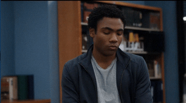 a man with a surprised look on his face is sitting in front of a bookshelf
