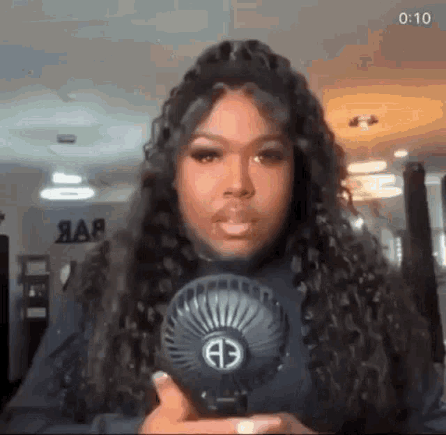 a woman with curly hair is holding a small fan in her hand .