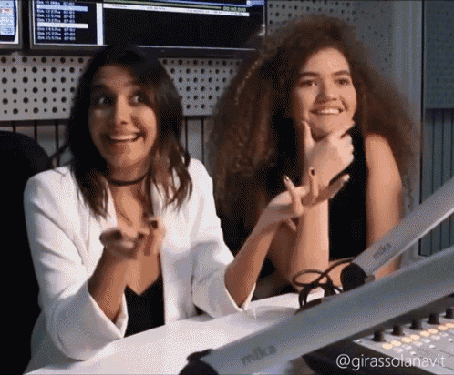 two women are sitting at a desk with a mike microphone