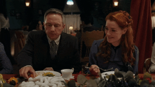 a man and a woman sitting at a table with plates of food