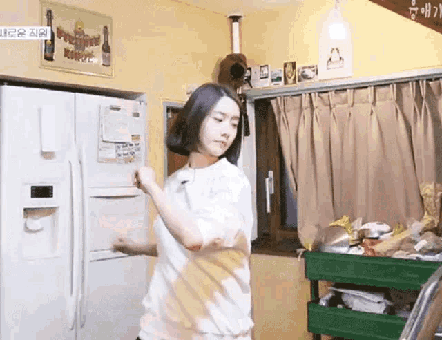 a woman is standing in front of a refrigerator .