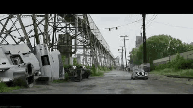 a car is driving down a dirt road in front of a large building .