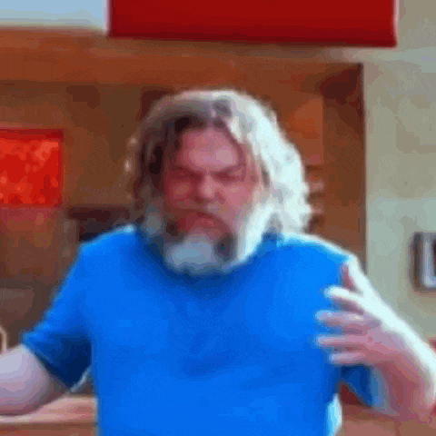 a man with long hair and a beard wearing a blue shirt is making a funny face .