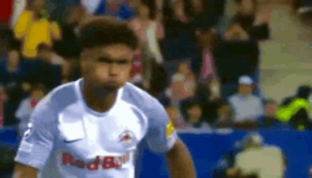 a soccer player in a white red bull jersey is running on the field .