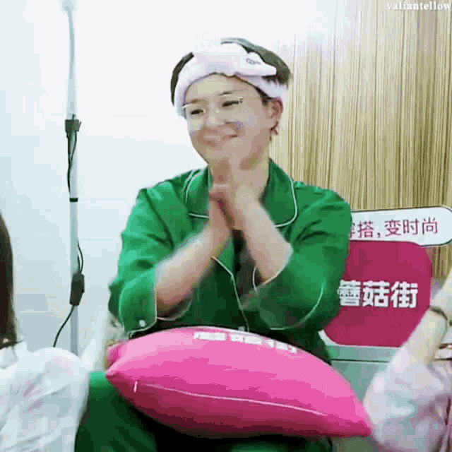 a woman wearing glasses and a headband is sitting on a pink pillow