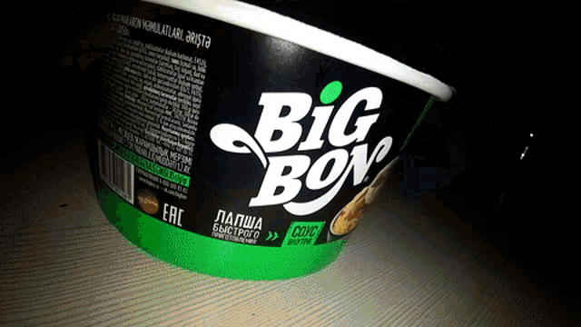 a green bowl of big bon noodles sits on a table