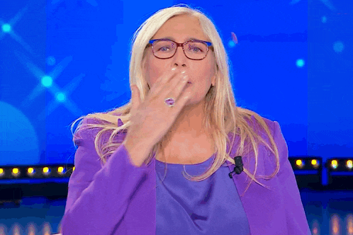 a woman in a purple jacket is blowing a kiss