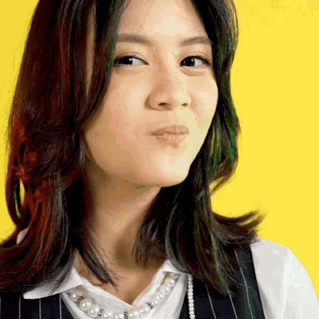 a woman wearing a pearl necklace and a white shirt