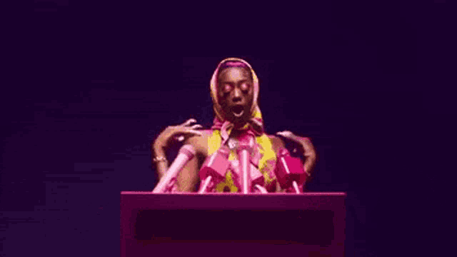 a woman is standing in front of a crowd of microphones .