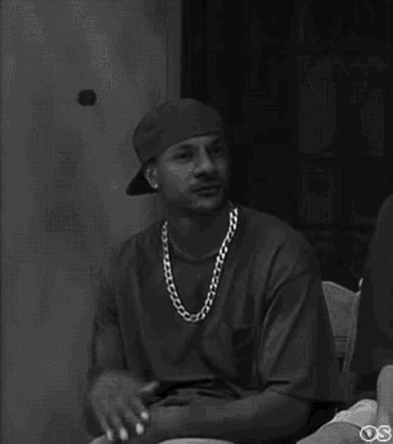 a black and white photo of a man wearing a bandana and a necklace .