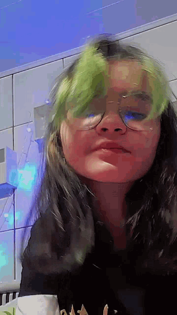 a girl with green hair and glasses is making a face