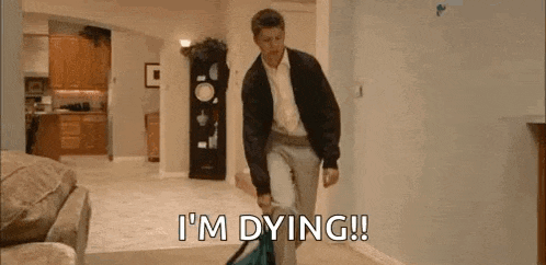 a man is carrying a bag in a living room and says `` i 'm dying '' .