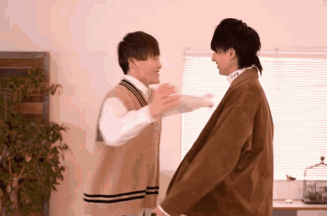two young men are hugging each other in front of a window with the word love on their collar