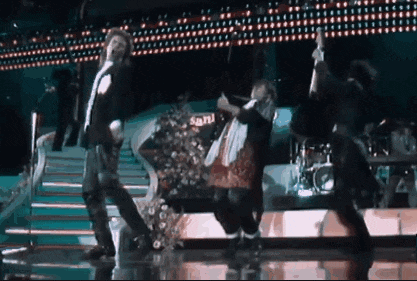a group of people are dancing on a stage in front of a sign that says sand
