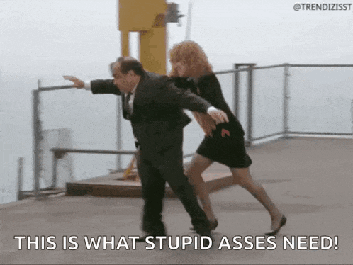 a man in a suit and a woman in a black dress are dancing on a balcony with the caption this is what stupidasses need