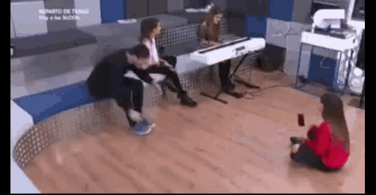 a woman is sitting on the floor in front of a piano while a man sits on a bench .