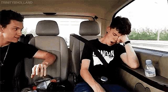 two men are sitting in the back seat of a car .