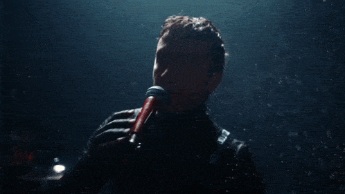 a man singing into a microphone with a black shirt that says calvin klein