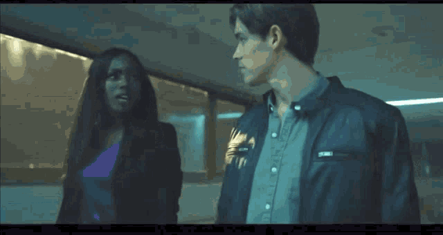 a man and a woman standing next to each other in a dark room