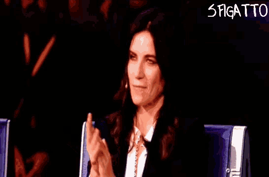 a woman is clapping her hands in front of a sign that says stigatto