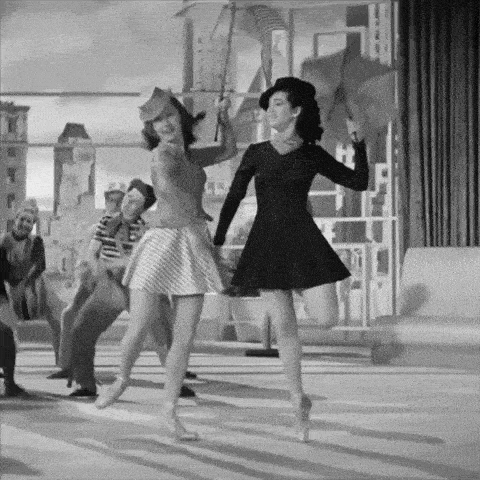 a black and white photo of two women dancing in front of a crowd
