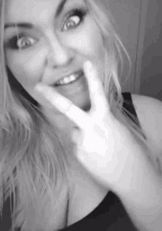 a woman is making a peace sign with her hands .