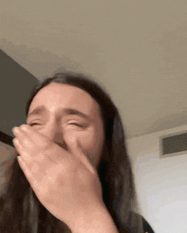 a woman is covering her mouth with her hands while crying .