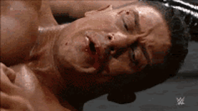 a man with blood on his face is laying on the ground with his eyes closed .