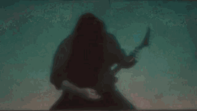 a man in a hood is playing a guitar on a screen