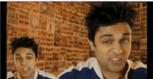 two men are standing next to each other in front of a wall .