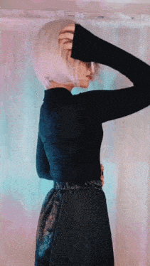 a woman with short blonde hair is wearing a black turtleneck and a black skirt