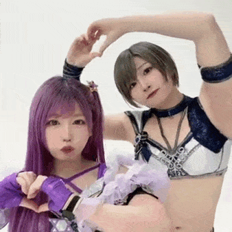 two women are standing next to each other making a heart shape with their hands .
