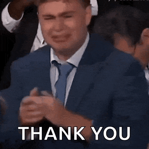 a man in a suit and tie is crying in a crowd and saying thank you .