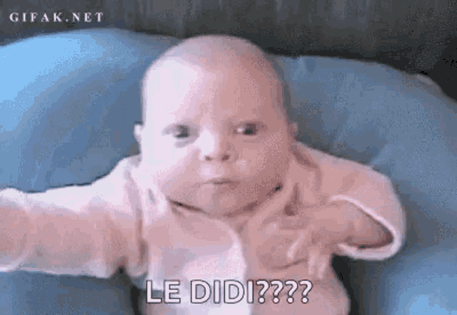 a baby is laying on a blue pillow and making a funny face while looking at the camera .