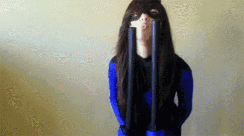 a woman in a blue superhero costume is holding two black poles in her hands
