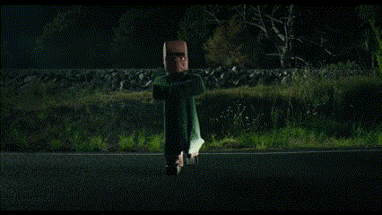 a person in a mask is standing on the side of the road