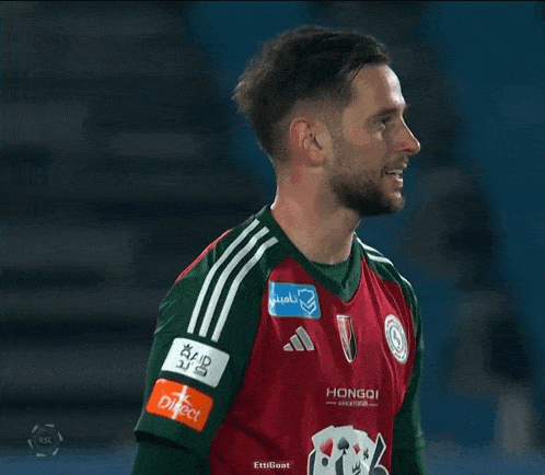 a soccer player wears a red and green jersey with a hongoi logo on the sleeve