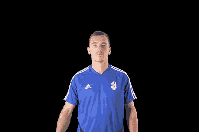 a man in a blue adidas shirt flexing his muscles