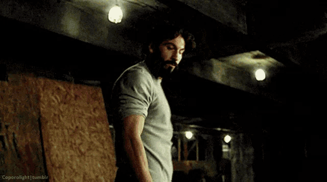 a man with a beard is standing in a dark room in a room .