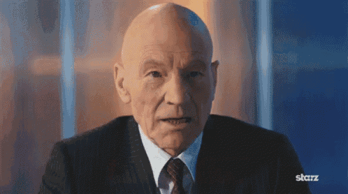 a bald man wearing a suit and tie is sitting in front of a starz logo
