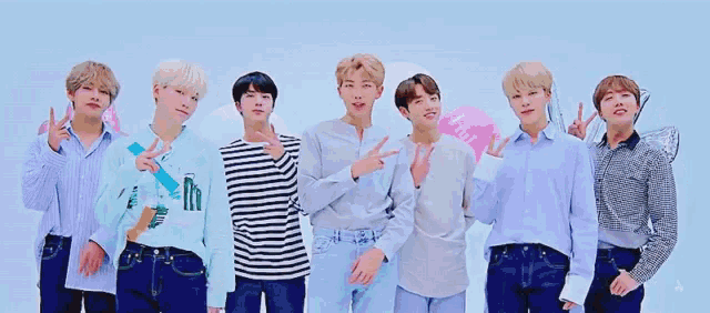 a group of young men standing next to each other giving peace signs .