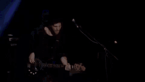 a man is playing a guitar and singing into a microphone with a laney amp in the background