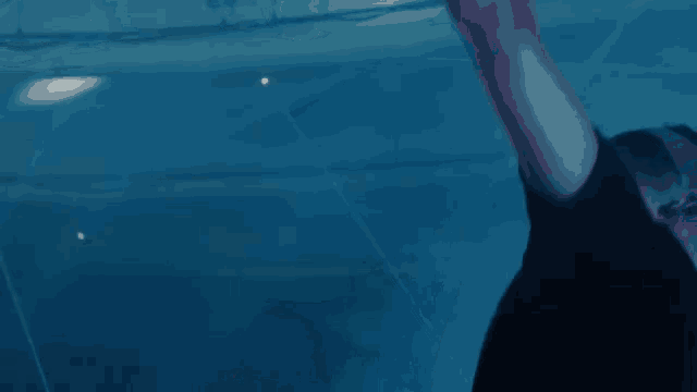 a person in a black shirt is standing in a pool with their arm up
