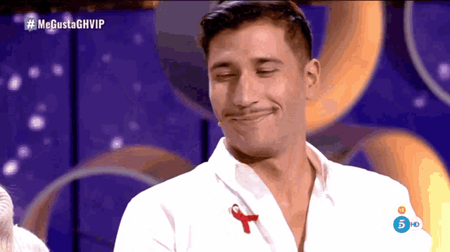 a man wearing a white shirt with a red ribbon on it is on a television show