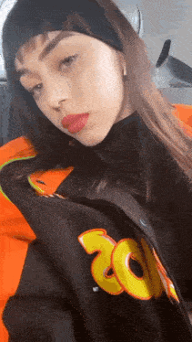 a woman wearing a black headband and an orange jacket with the number 20 on it